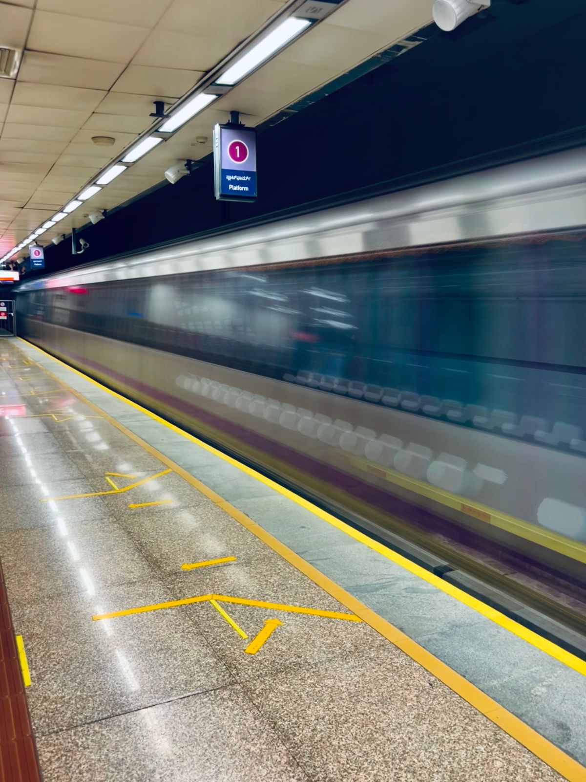 A subway train blurring past an underground platform
